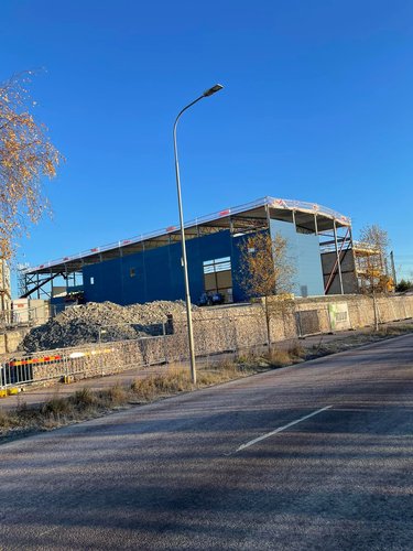 Kommersiell byggnad under konstruktion med ställningar och blå fasad
