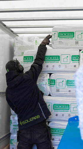 Isolerab-medarbetare plockar ISOCELL-säckar från stapel i lastbil under isoleringsarbete