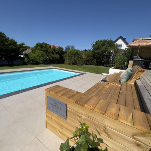 Karlssons Stensättning färdigställer uteplats med träbänk, beige plattsättning och pool i grönskande miljö