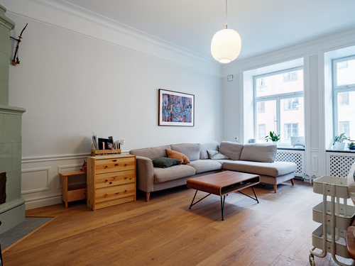 Ljust vardagsrum med parkett, soffa och byrå i renoverad sekelskiftesvåning, renoverat av Jobryan
