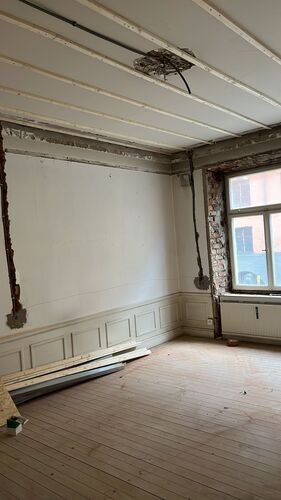 Rum under renovering med panel, takrosett och gamla lister bevarade