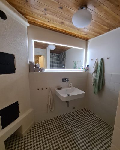 Renoverat badrum i Täby med väggmonterat handfat, belysning och klassiskt rutmönstrat golv