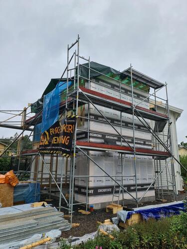 Pågående fasadrenovering av villa med byggställningar och skylt för L&A Bygg och Renovering