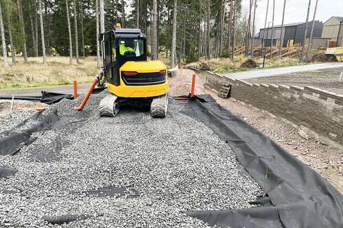 Liten bandmaskin på förberedd yta med fiberduk och grus