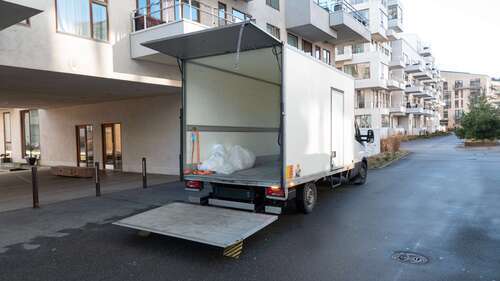Tom flyttbil parkerad vid ett bostadshus med nedfälld bakramp.