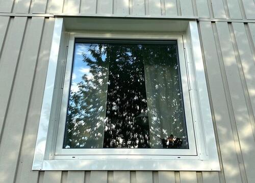 Energieffektivt fönster installerat på träfasad – speglar grönskande omgivning