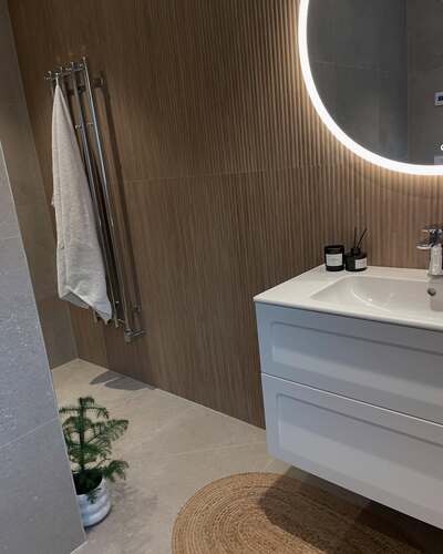 Badrum i Sandviken med vägghängd kommod, naturfärgade plattor och LED-spegel – exempel på elegant VVS-arbete av LA Rörsystem AB i Gävleområdet.