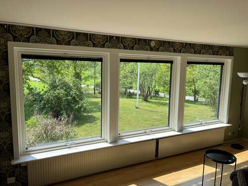 Tre fönster med vit karm sett från insidan av ett rum