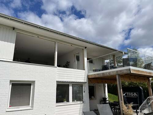 Bostadshus med vit fasad, balkong och fönster