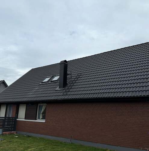 Nyrenoverat tak med svarta takpannor och takfönster på en enplans tegelvilla i Örebro.