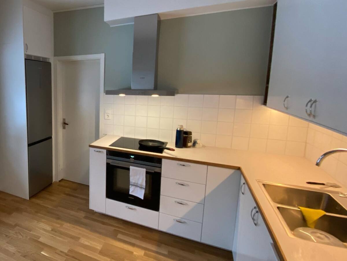 Modernt kök med vita luckor, kakel, spishäll och diskho, sett från sidan med bra överblick. Modernt kök med vita luckor, kakel, spishäll och diskho, sett från sidan med bra överblick.