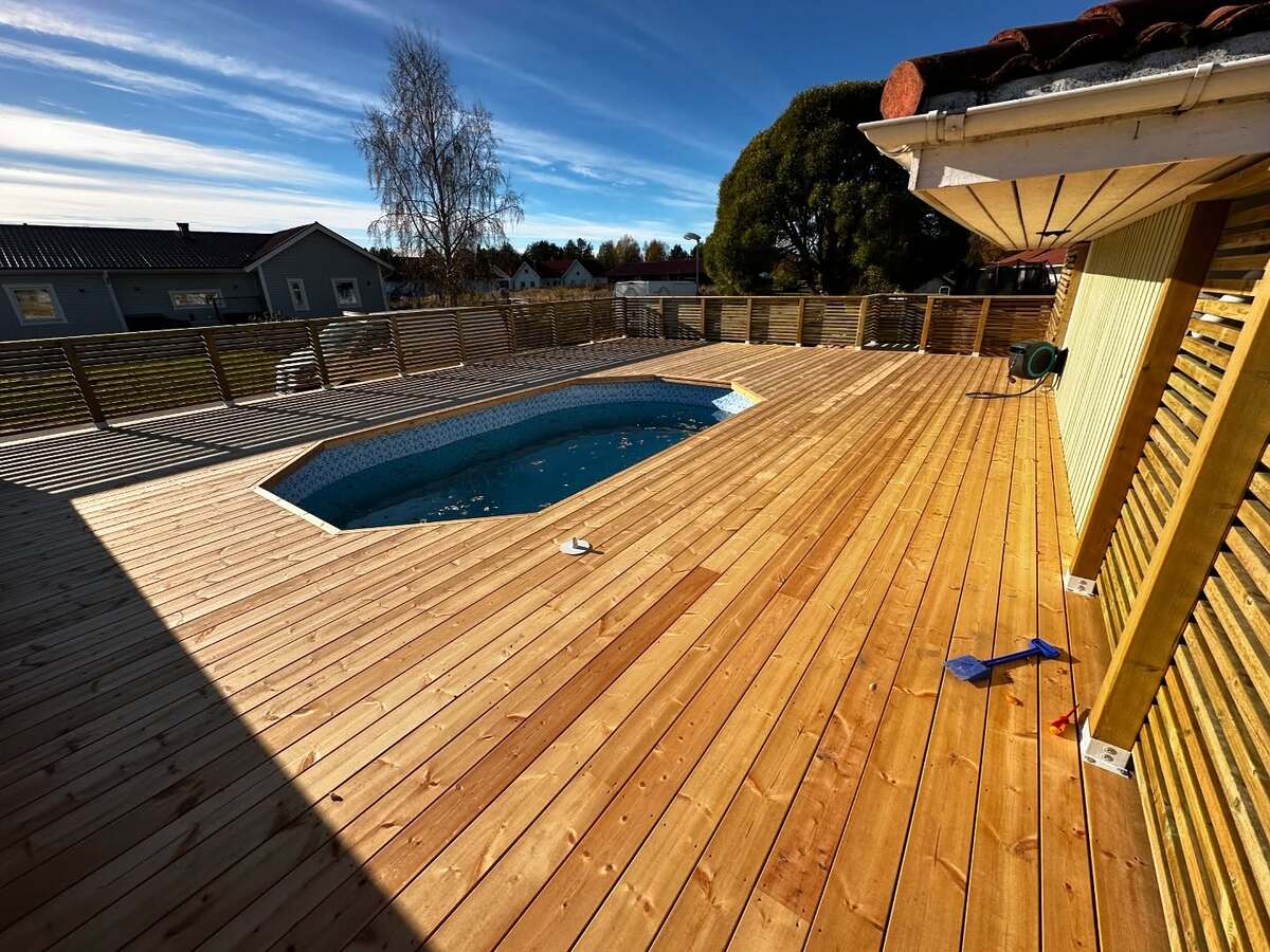 Altan i trä med inbyggd pool, omgiven av räcke och solbelyst av klar himmel. Altan i trä med inbyggd pool, omgiven av räcke och solbelyst av klar himmel.