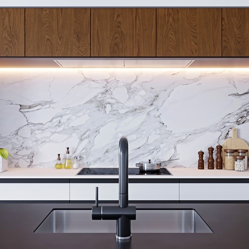 Modernt kök i Stockholm med träskåp, marmorvägg och stilren belysning