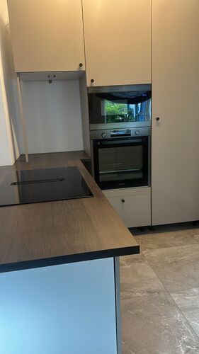 Rengjord inbyggd ugn och induktionshäll med grå bänkskiva i modernt kök