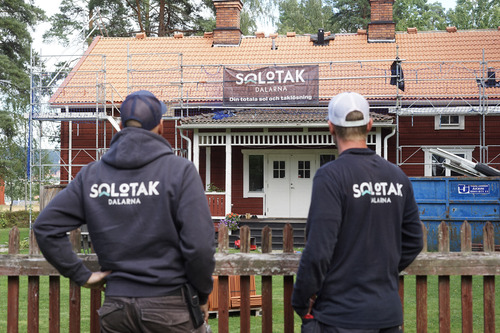 Solotak-medarbetare betraktar pågående takläggning på äldre hus med ställning