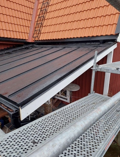 Nylagt falsat plåttak sett från ställning på rött hus