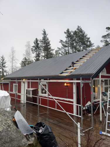 Takarbete på rött hus med byggställning