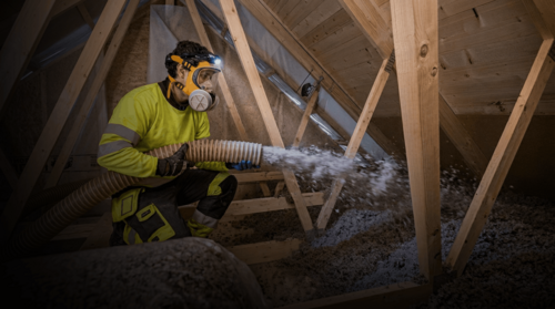 Installatör som sprutar lösullsisolering på vind i hus