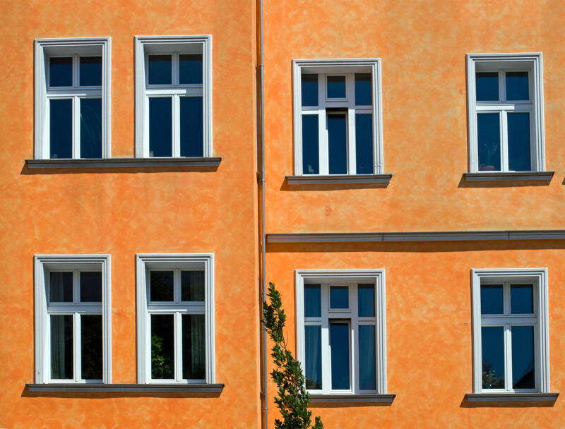 Putsfasad i orange kulör med vitmålade fönsteromfattningar