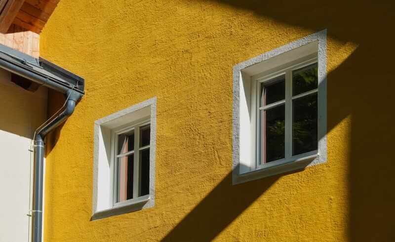 Putsfasad i gult med vitmålade fönsteromfattningar