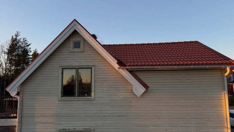 Vitt hus med rött tegeltak sett från takfoten