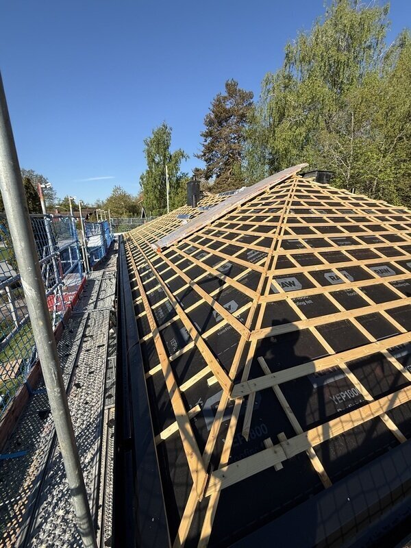 Tak under montage med läkt lagd på underlagspapp, byggnadsställning i bakgrunden