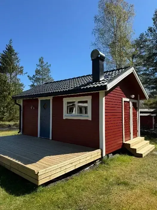 Rödmålad villa med nylagt svart tegeltak och altan
