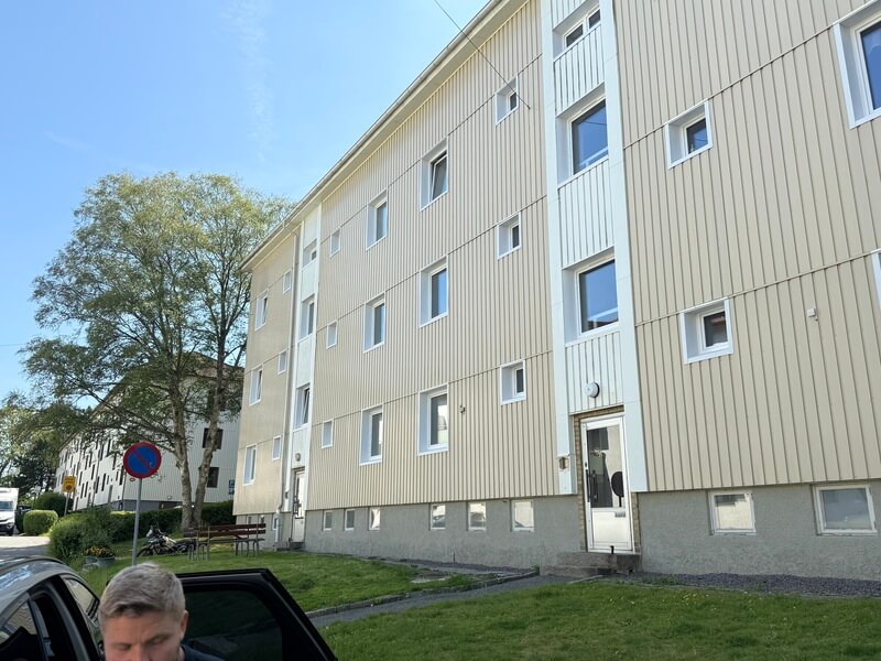 Flerbostadshus med nyinstallerade vita fönster sett från parkeringen