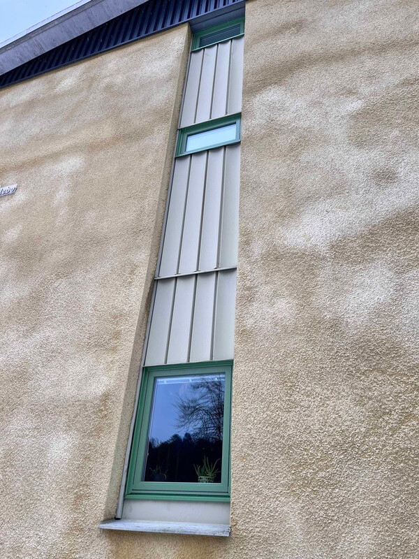 Närbild på grön fönsterprofil monterad mot putsad fasad