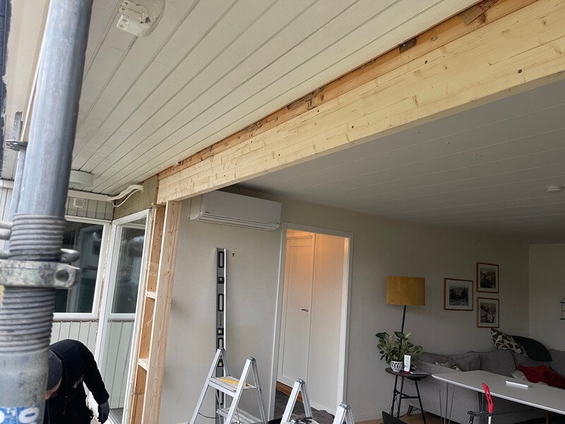 Närbild på ny träavväxling ovanför dörröppning under pågående fönsterbyte