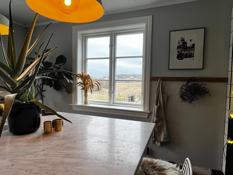 Nyinstallerat fönster med vit karm och utsikt över landsbygd i ljust matrum
