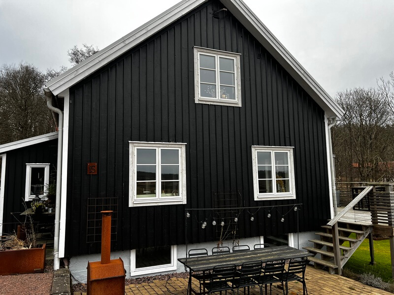 Mörk villa med svart träpanelfasad och nyinstallerade vita fönster