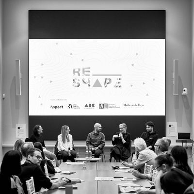 Long boardroom meeting table in modern room with high ceilings and large screen