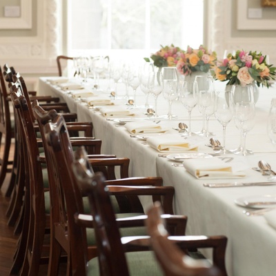 A row of chairs prepared at a dining table for a wedding dinner