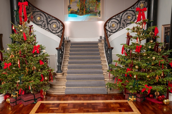 The staircase in the lobby, with two lit up Christmas trees on either side of the staircase