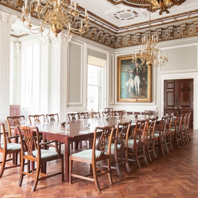 A formal meeting set in a boardroom layout in a grand room  