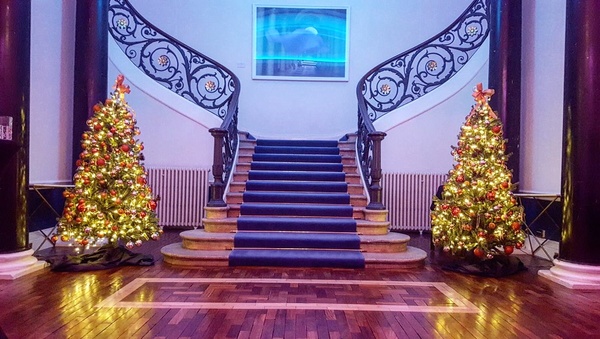 The staircase in the lobby, with two lit up Christmas trees on either side of the staircase