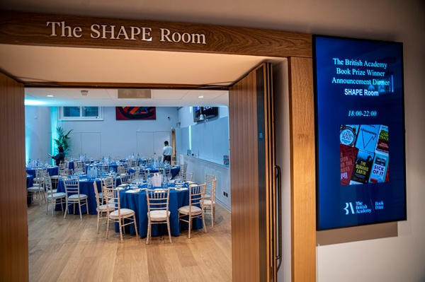 The entrance to the SHAPE Room, where the room is set up with round tables for dining