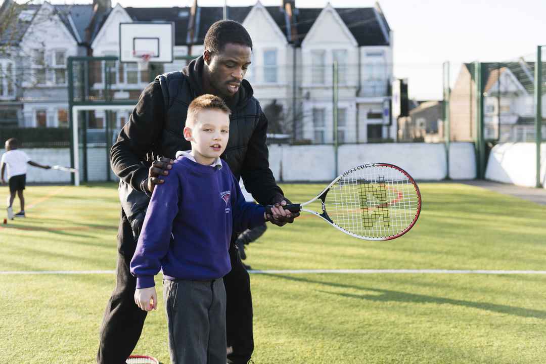 school child learning how to play tennis