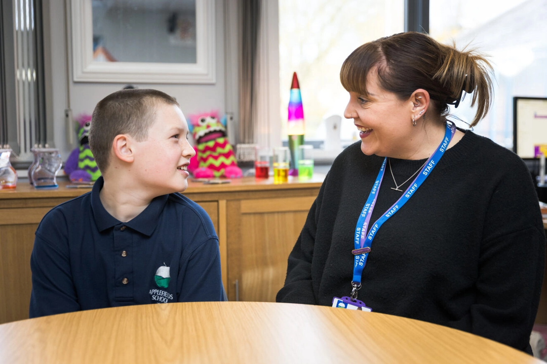 Photo of a teacher and pupil smiling at each other