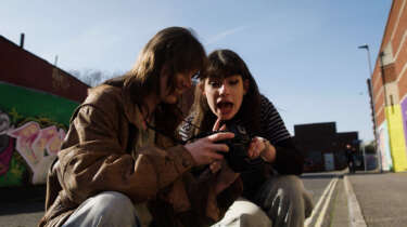 A young woman shows a mentor her photography on her camera. The mentor is enthusiastic about the work she's done.