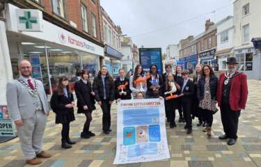 Young people and the council stand and pose for the camera holding up the sign which launches the way finding scheme in Littlehampton.