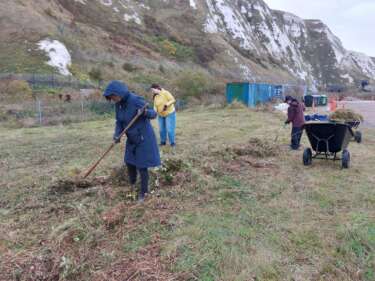 Artswork staff use rakes and shovels to clean up a grassy area