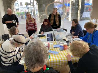 people sitting round a table doing a creative activity led by young people