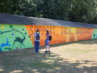 two people stand in front of a large colourful mural that is 40m long.