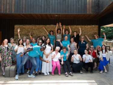 Artswork staff members pose for a silly photo, all are smiling and laughing with arms waving in the air