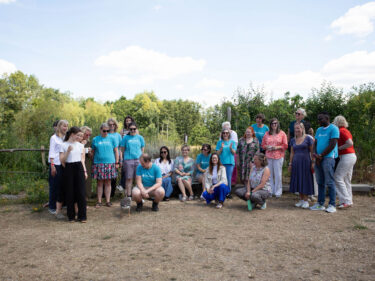 The Artswork team at their last staff away day, several members of the team are looking down at a Goose that has joined the group photo.