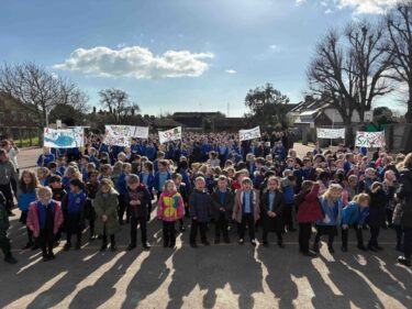 Whole school of primary pupils on playground facing the camera with protest banners