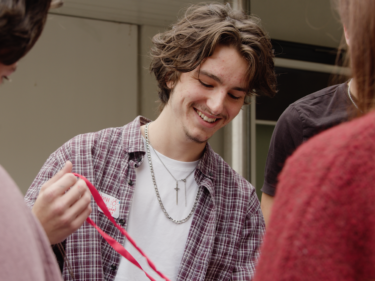 Young Man smiles and looks down as he untangles some string