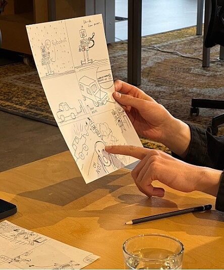 person holding sheet of paper with hand drawn cartoon pointing to it